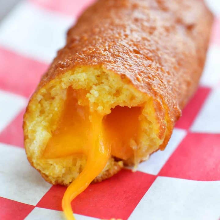 close up photo of fried cheese on a stick with a bite out of it and cheese oozing out