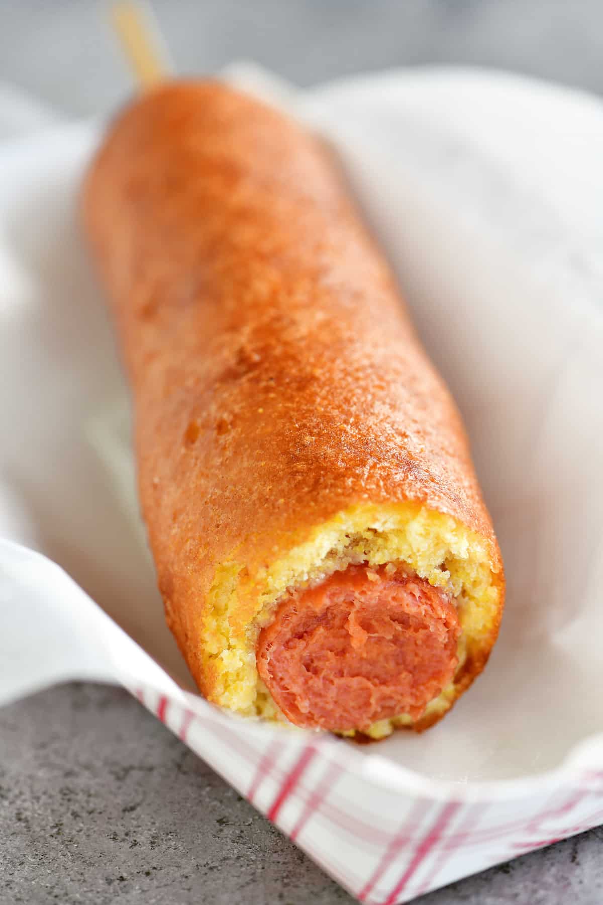 corn dog on a paper food tray with a bite out of it