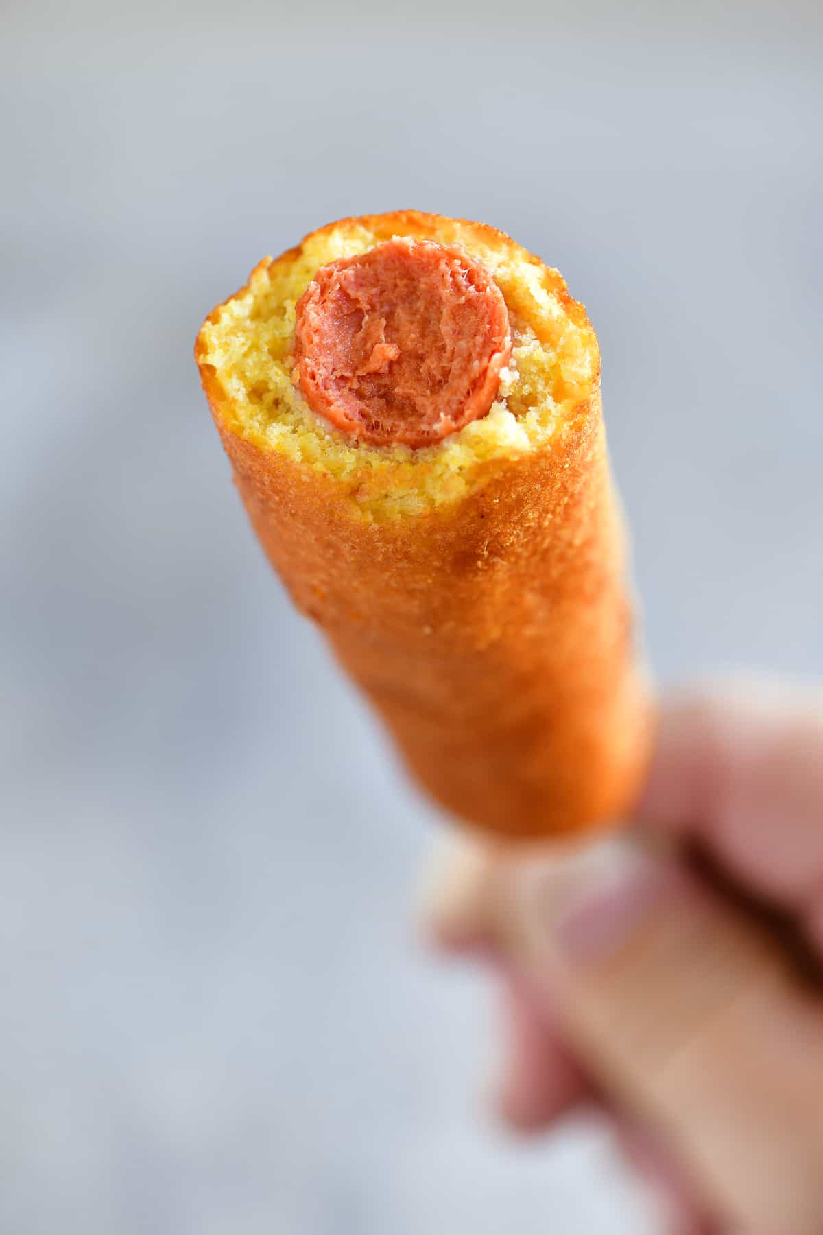 hand holding corn dog with a bite out of it
