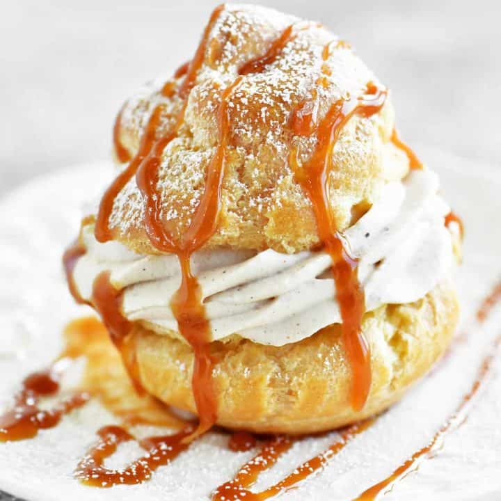 a caramel apple cream puff on a plate with caramel drizzled on top