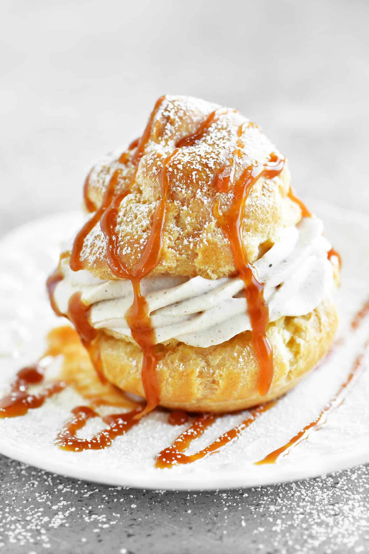 a caramel apple cream puff on a plate with caramel drizzled on top
