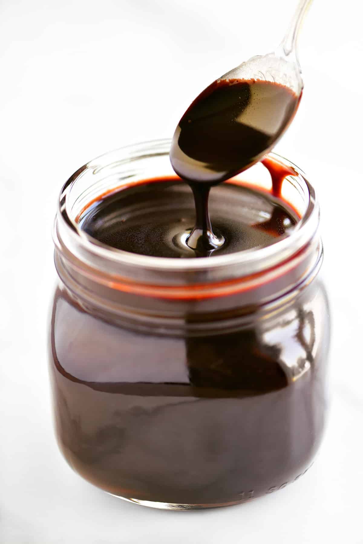 dipping a spoon in a jar of chocolate sauce