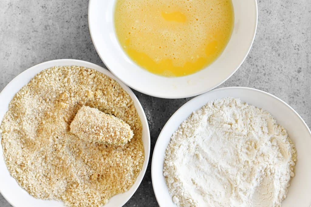three bowls containing flour, eggs and breading