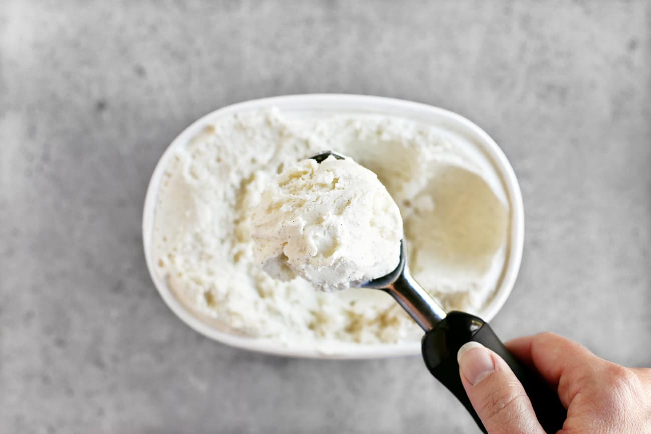 scooping vanilla bean ice cream from the container