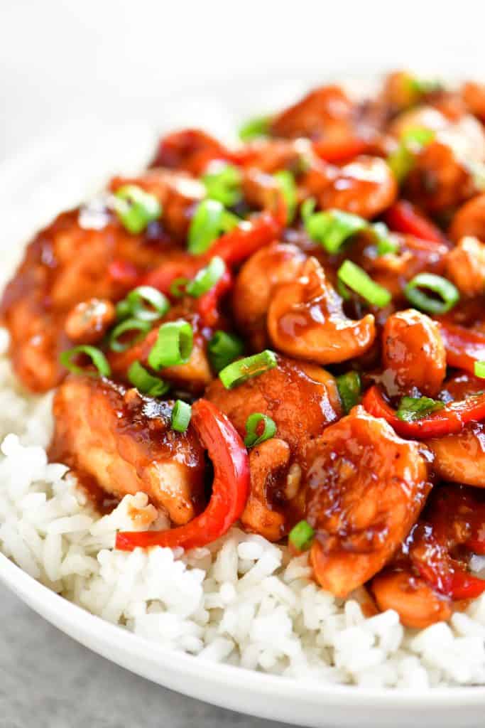 side view of cashew chicken on rice in a bowl