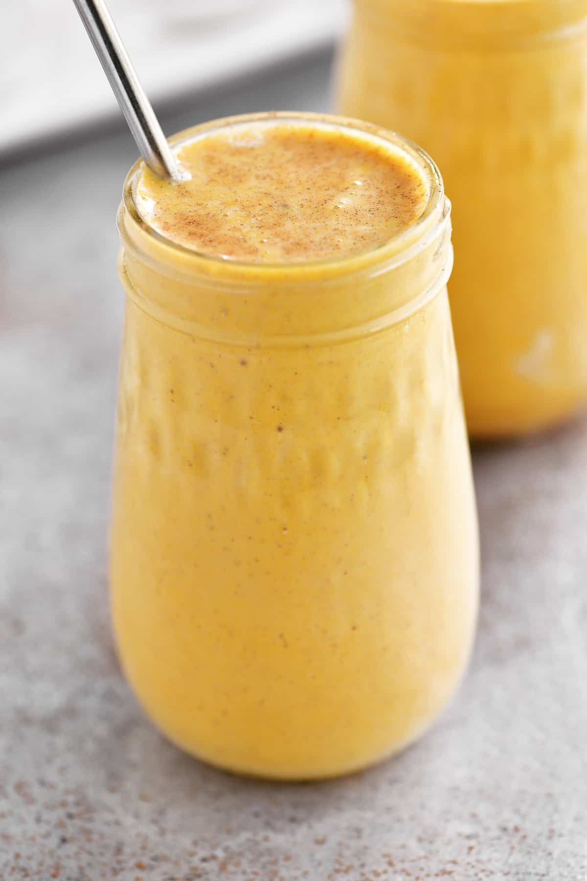 a pumpkin flavored smoothie in a glass jar drinking cup