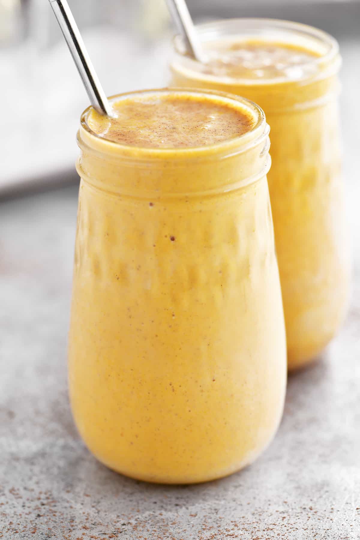 two pumpkin pie smoothies with metal straws