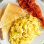 a topdown view of scrambled eggs, toast and bacon