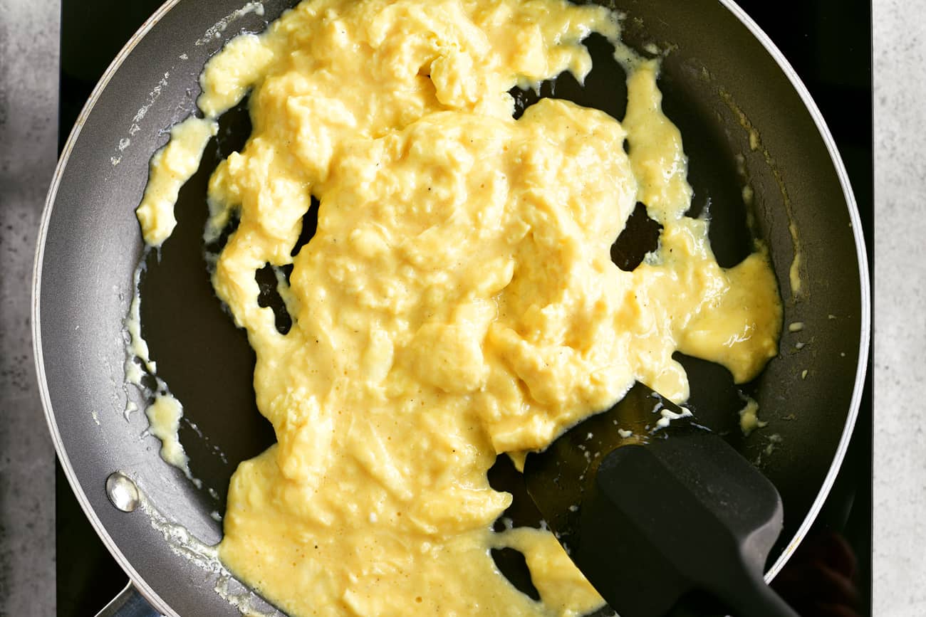 using a spatula to scramble eggs in a pan