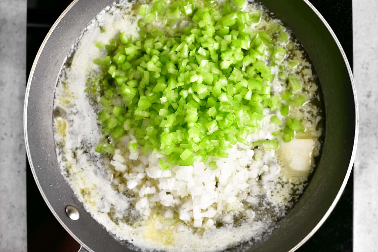 a photo of onion and celery in a frying pan with butter