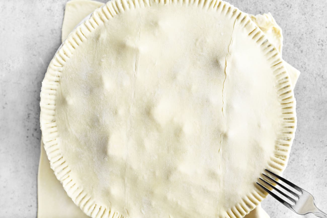 place the pie crust over the bowl and crimp the edges