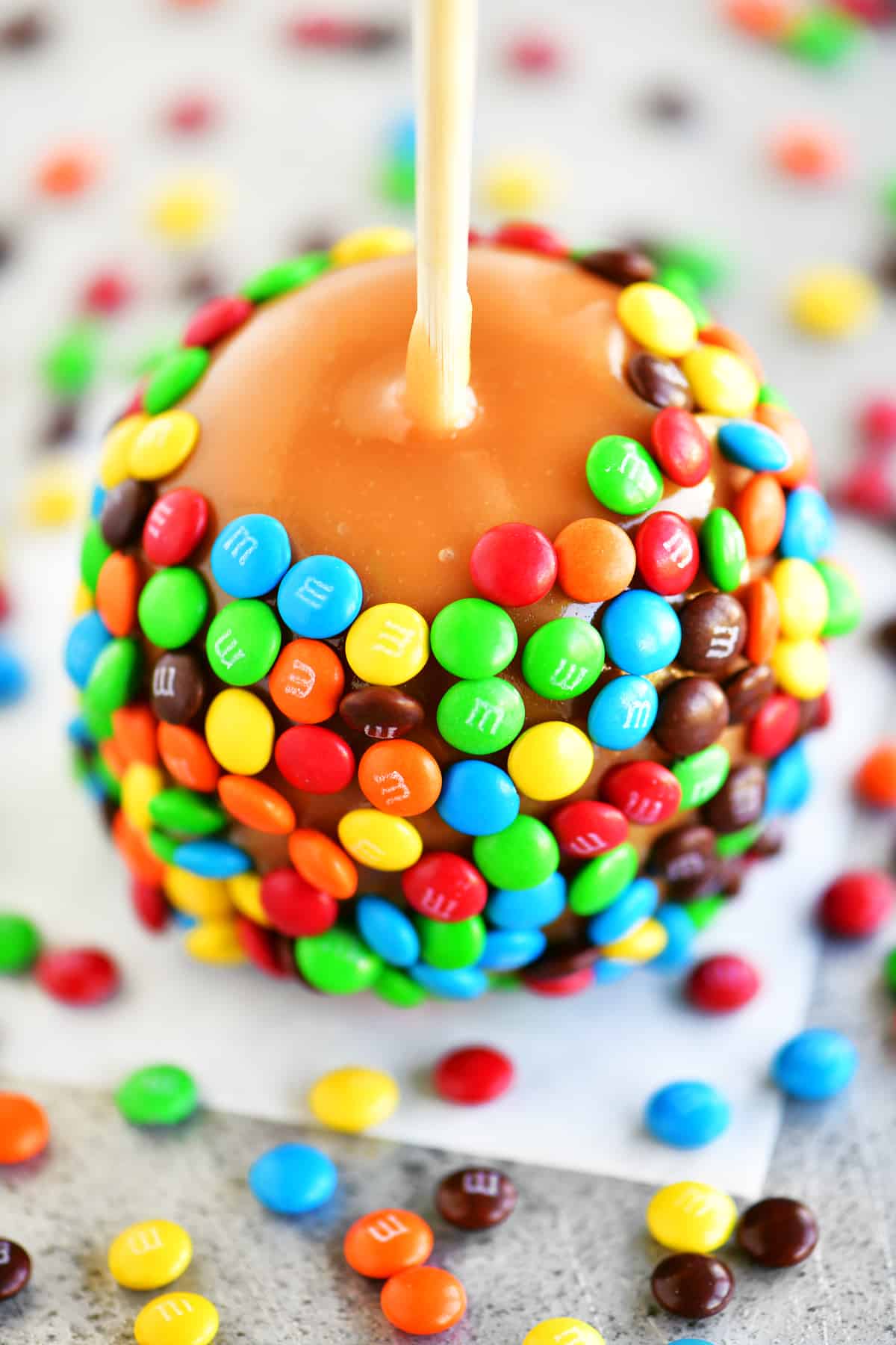 a colorful caramel apple that was dipped in mini M&M candies