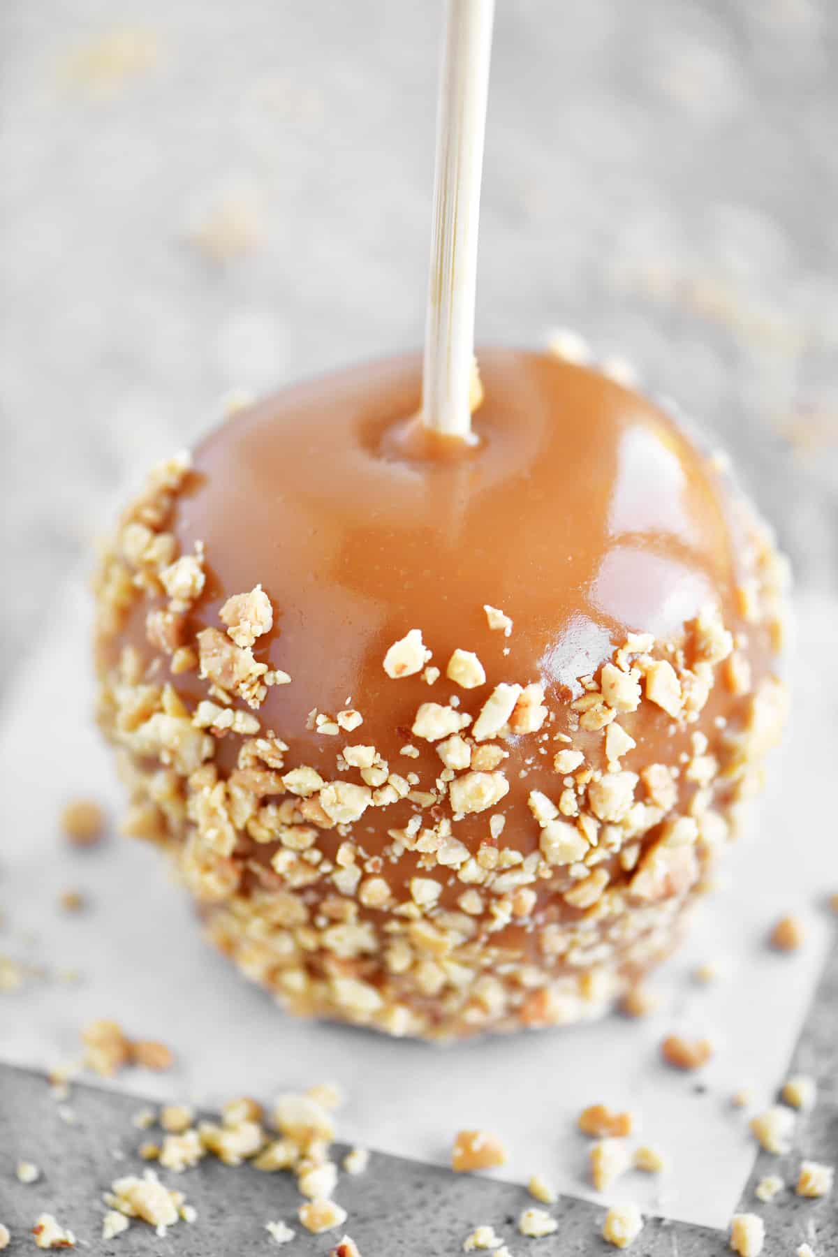 a caramel apple with a chopped nut topping