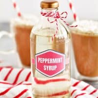 a photo of a bottle of peppermint coffee syrup with some mocha drinks in the background