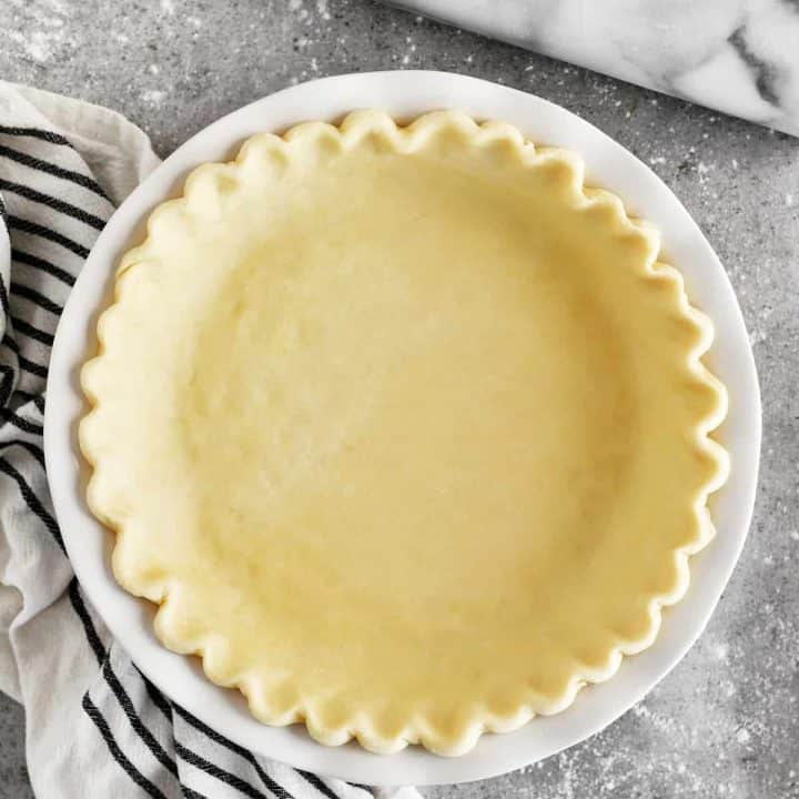 fluted pie crust in a pie plate with rolling pin