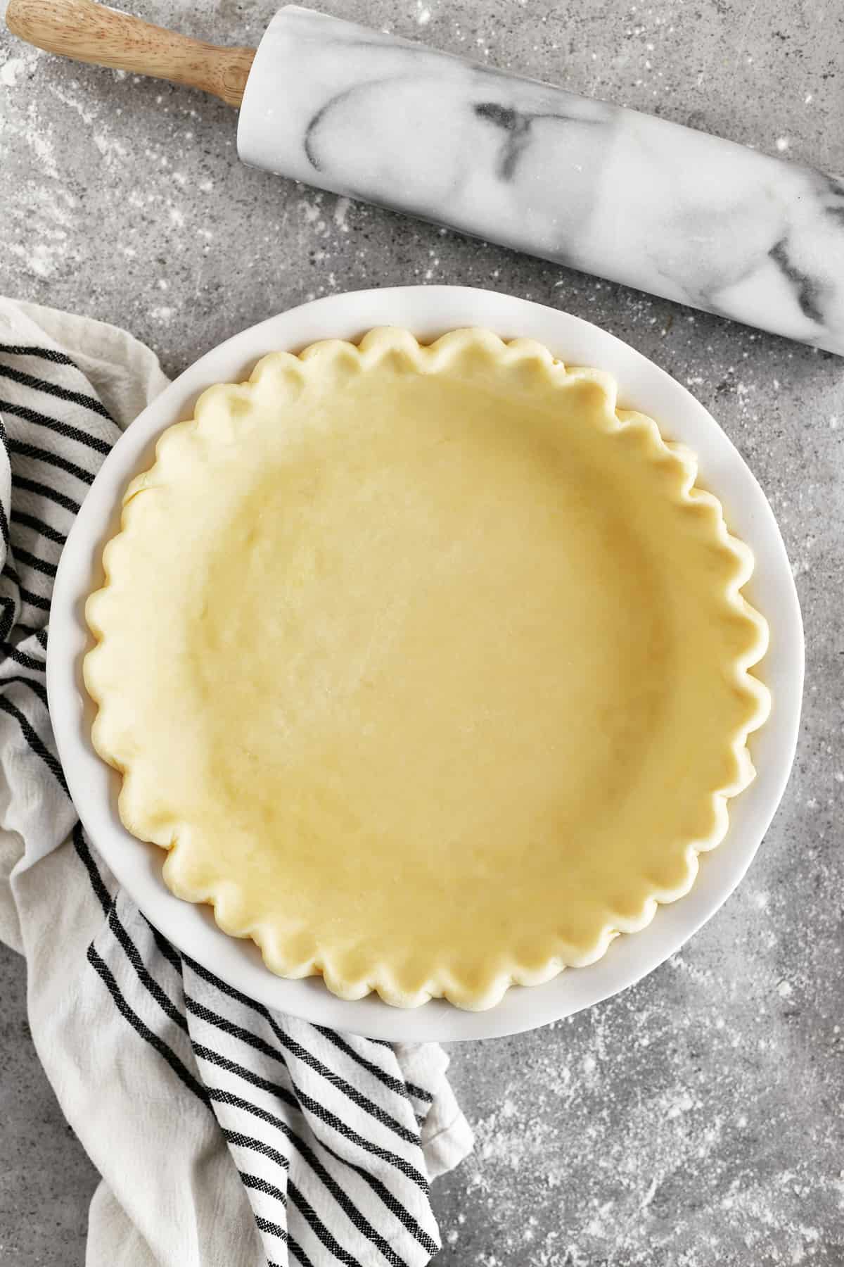 fluted pie crust in a pie plate with rolling pin