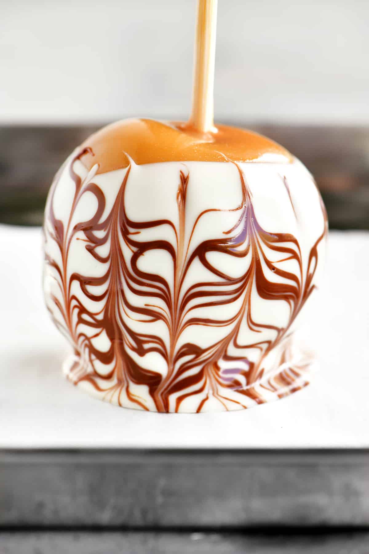 a caramel apple with a white and brown chocolate spiderweb design