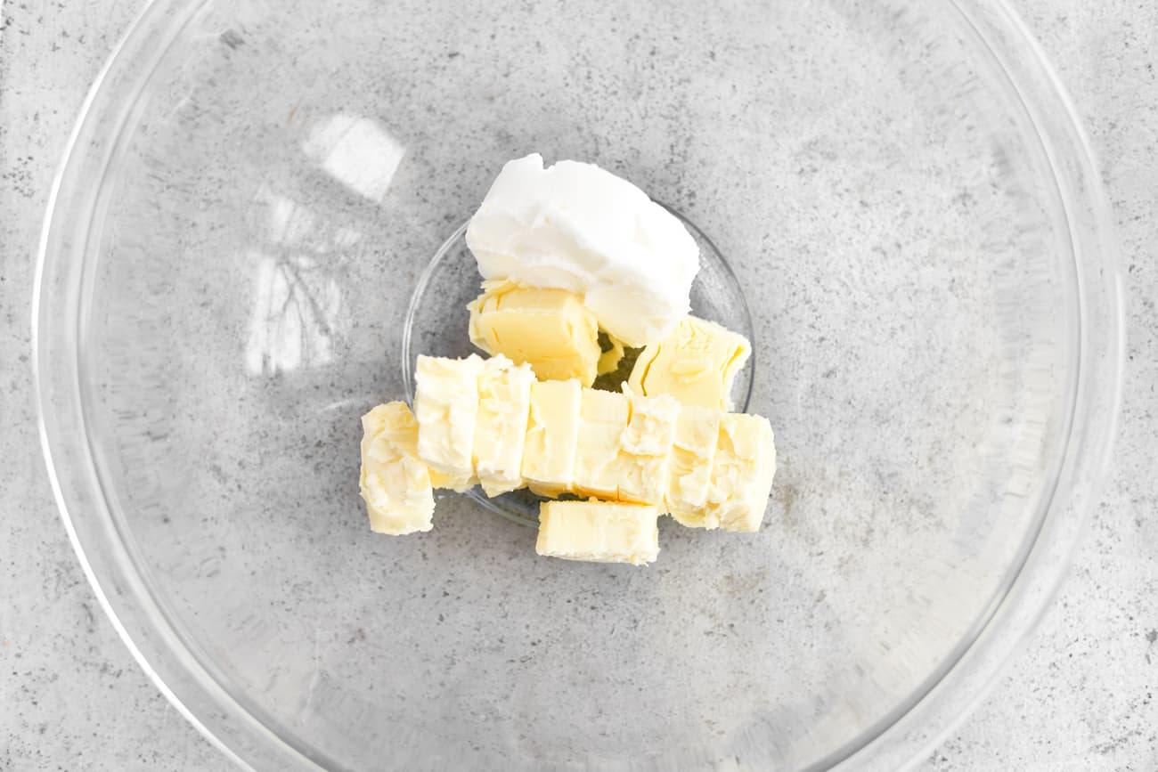 adding butter and cream cheese to a glass mixing bowl