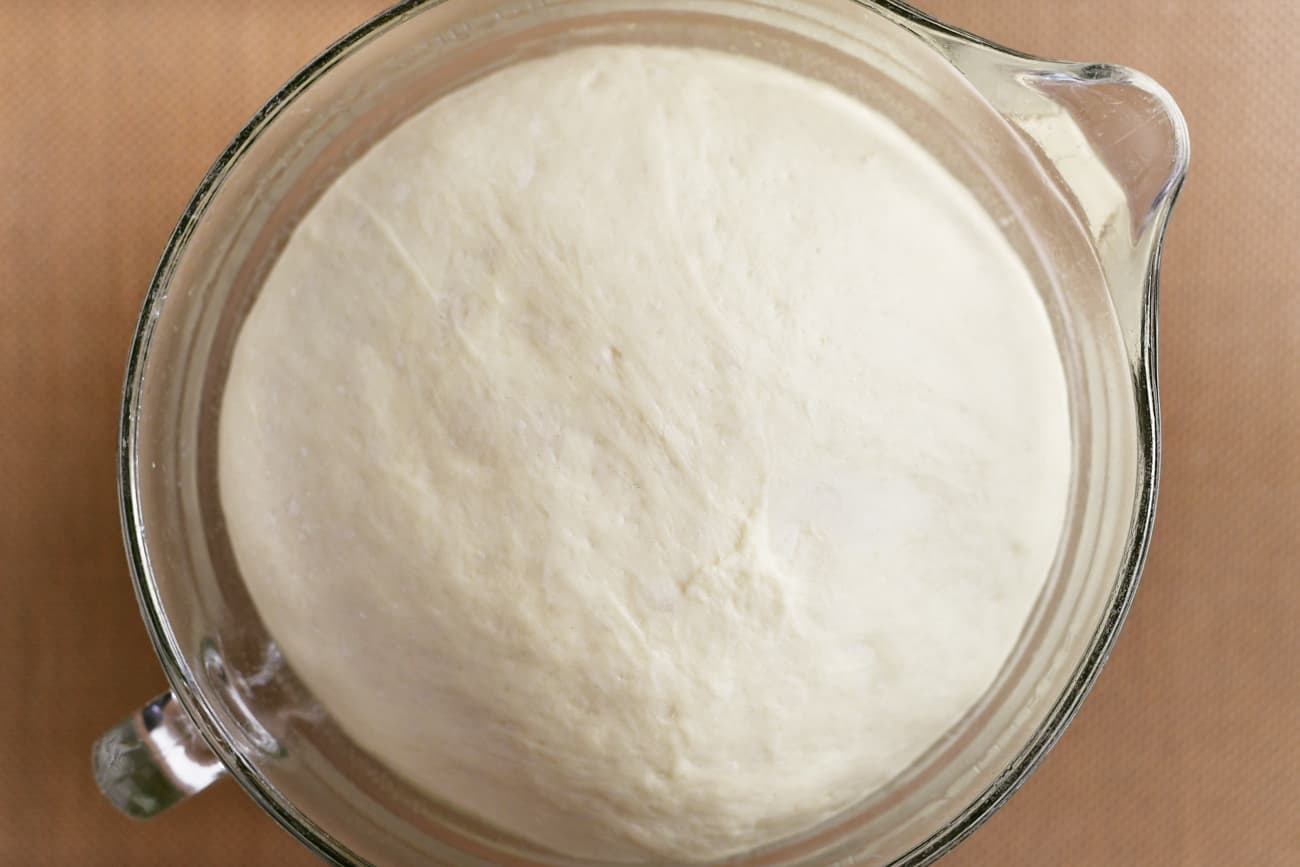risen dough under plastic in the bowl