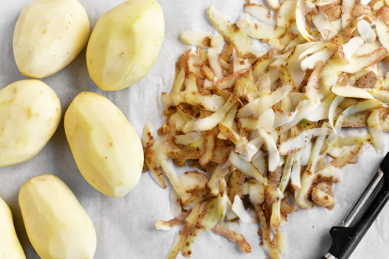a topdown photo of peeled potatoes on a cutting board