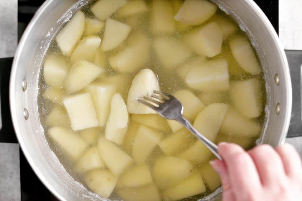 testing the softness of the potatoes with a fork