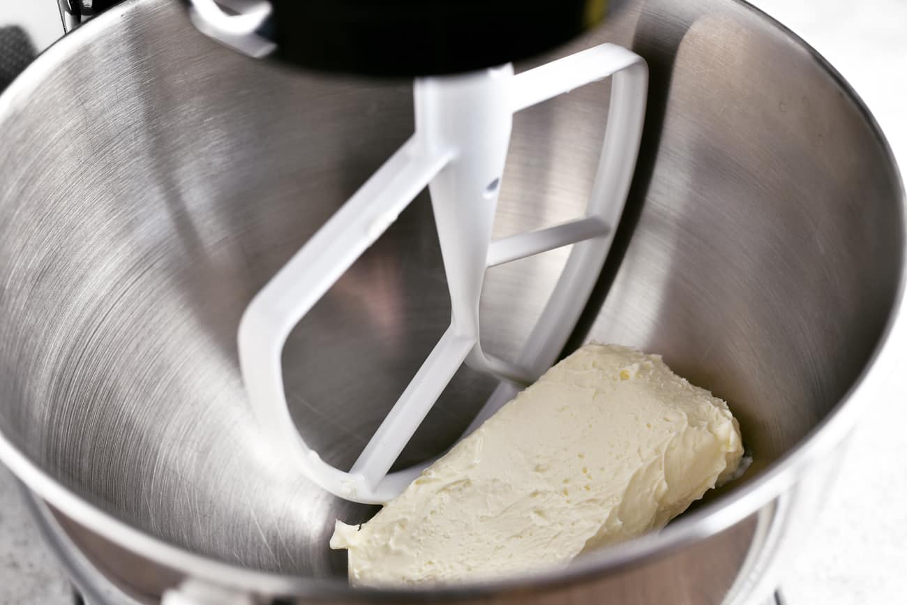 adding cream cheese to the mixer bowl