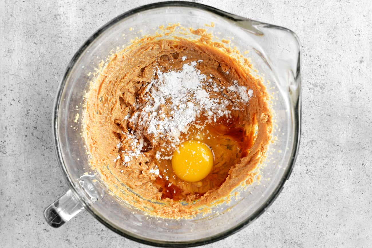 adding an egg and flour to the peanut butter and sugar mixture