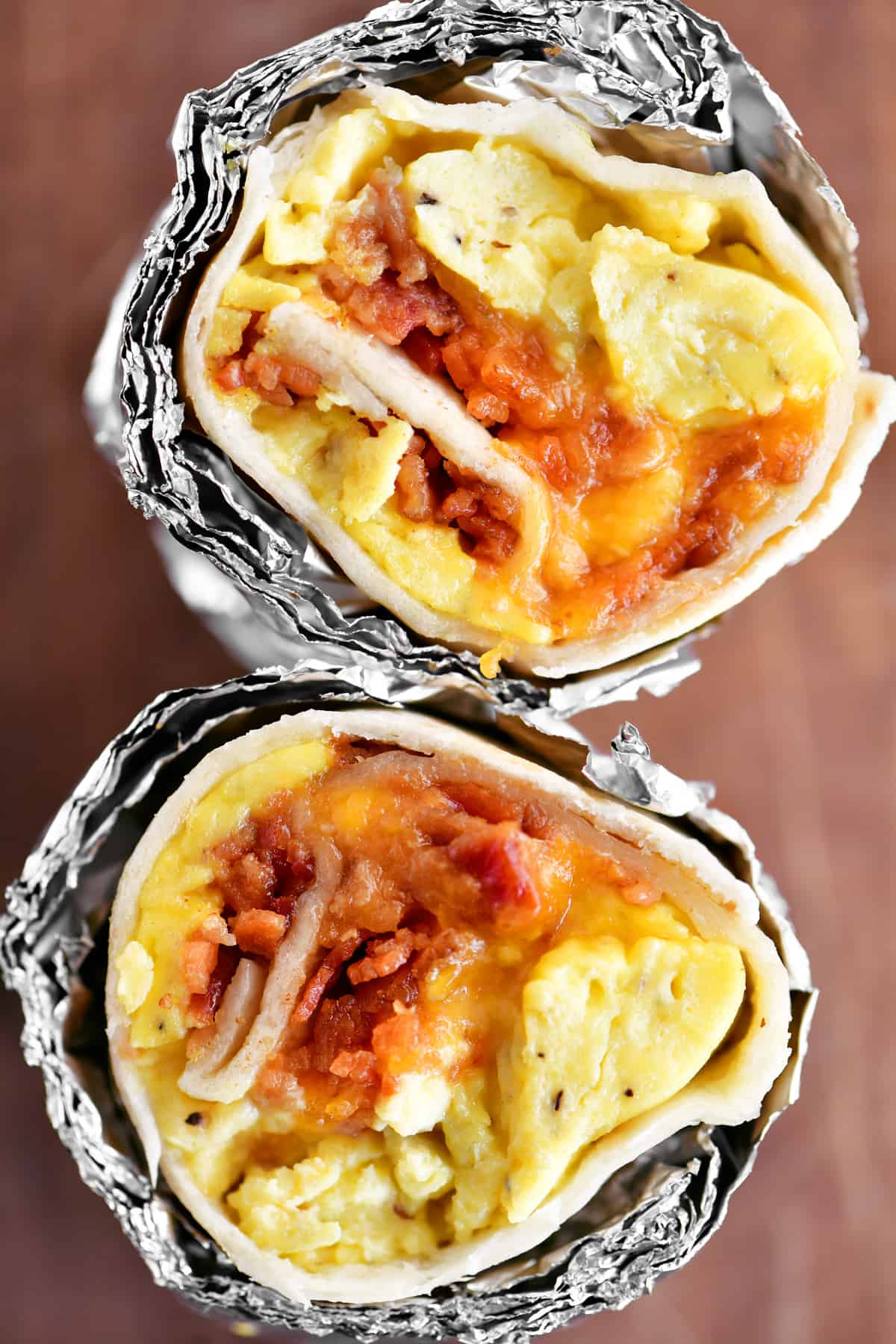 two halves of a breakfast burrito filled with bacon eggs and cheese