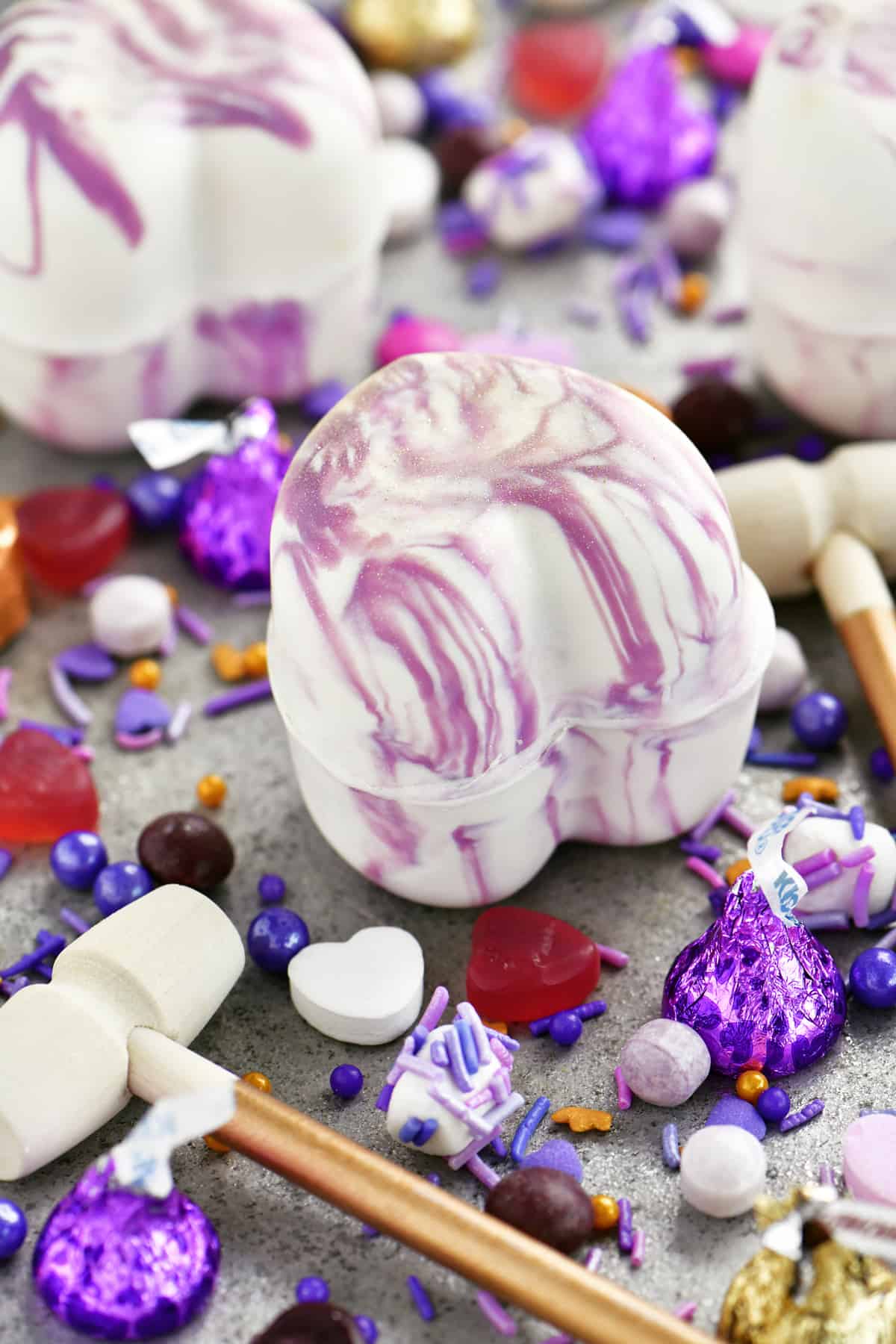 white chocolate heart with purple swirls, candy, sprinkles, and a mini hammer