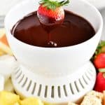 a strawberry being dipped into the chocolate fondue mixture