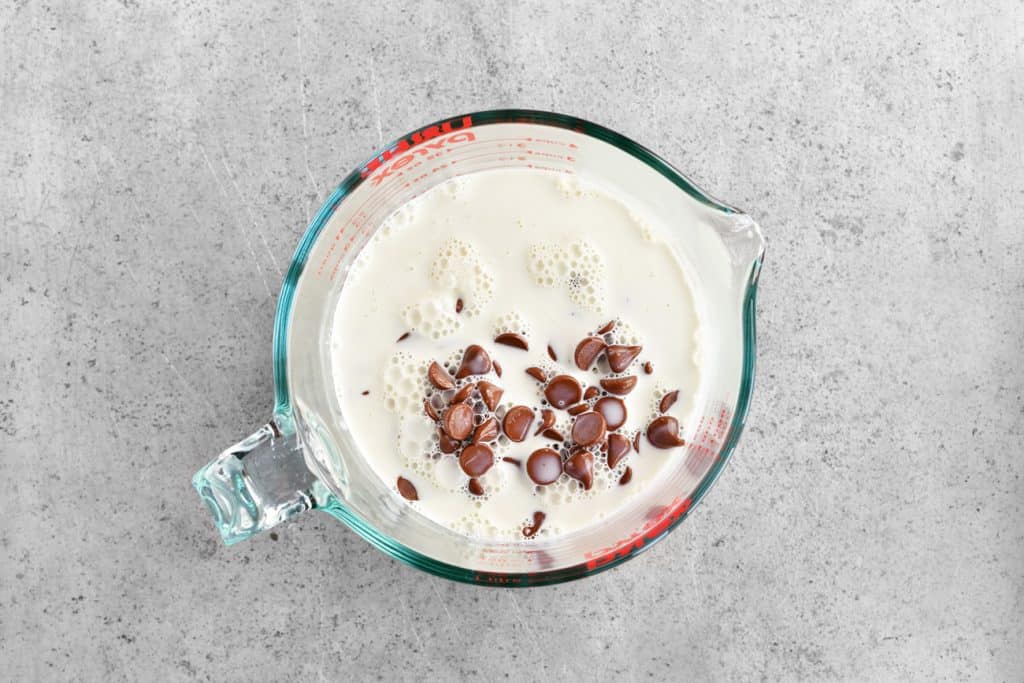a mixing bowl with cream and chocolate chips inside