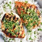 a photo of two cilantro-lime chicken breasts in rice