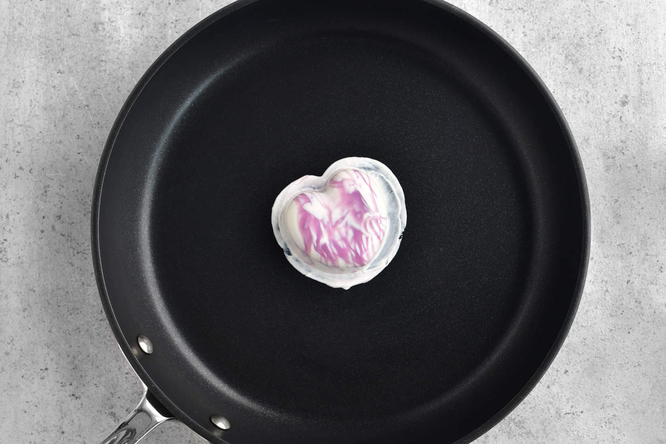 a purple and white hot chocolate bomb in a frying pan