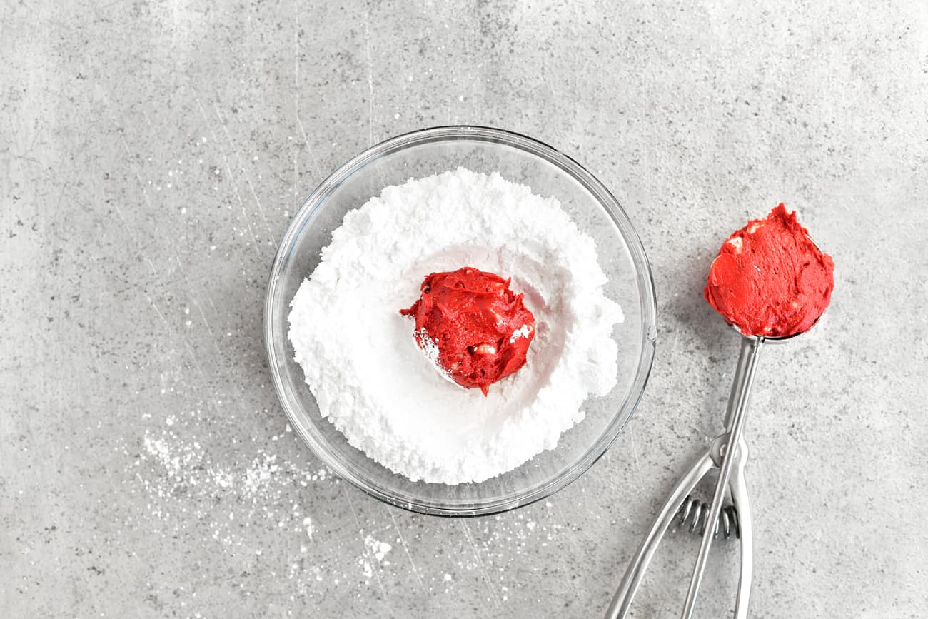 coating red velvet cookie dough balls with powdered sugar
