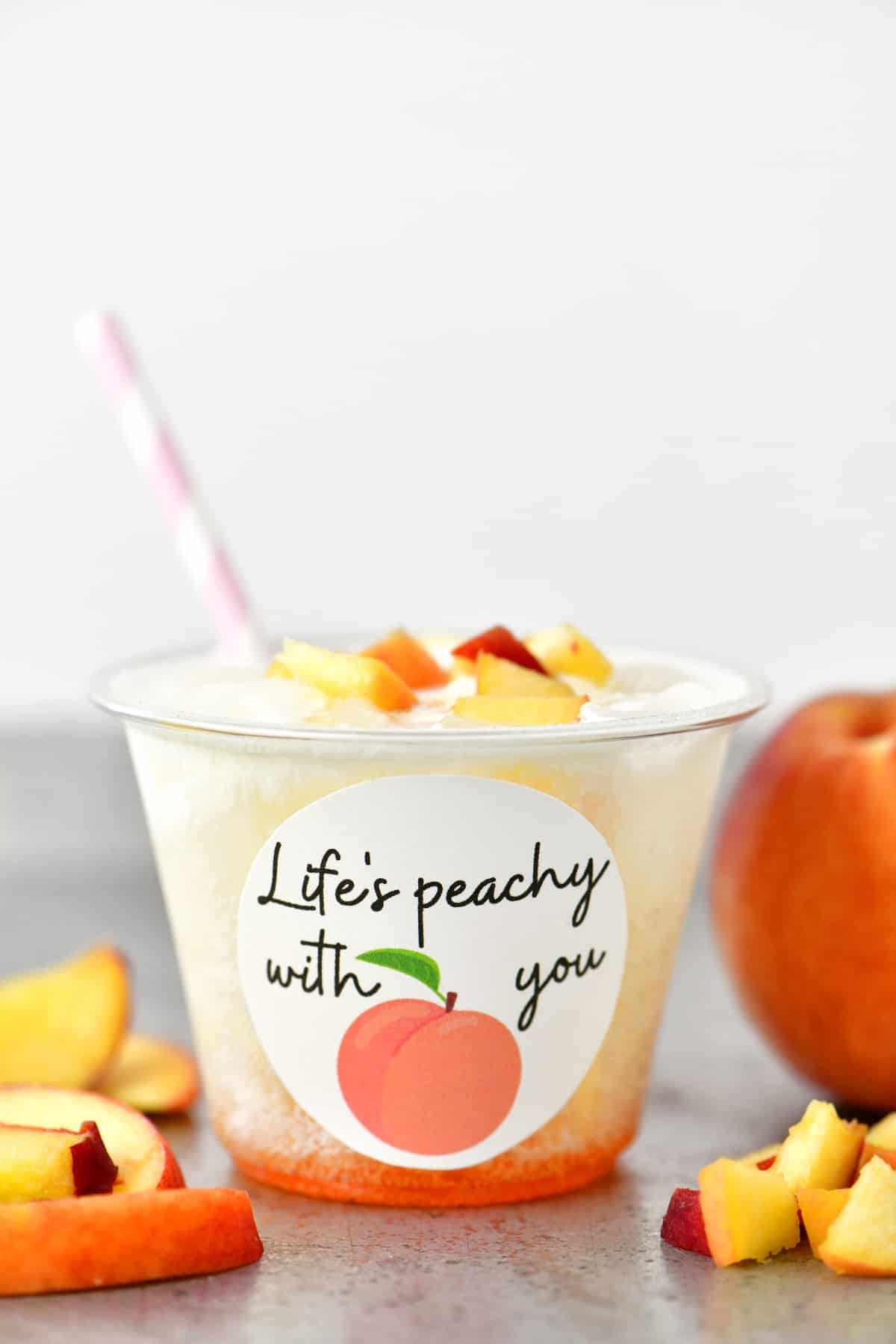 a peach flavored valentines drink in a clear cup with a pink and white striped straw