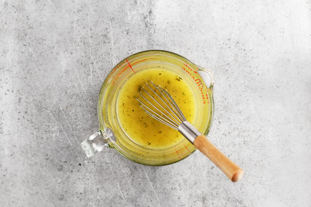 a whisk in a mixing cup filled with melted butter and spices