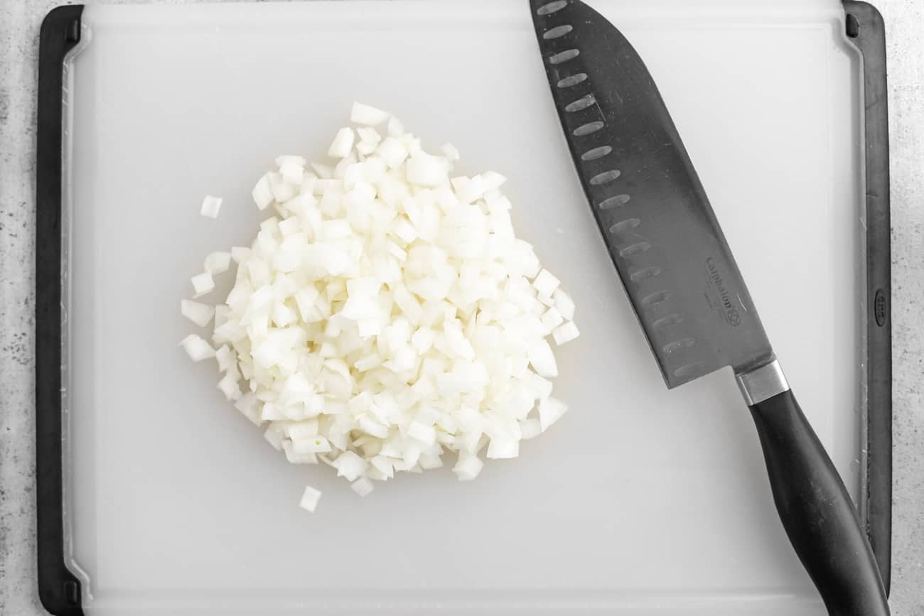 a knife and chopped onions on a cutting board