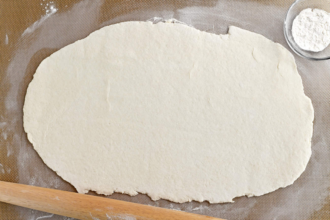 rolled out dough with rolling pin and flour in a bowl