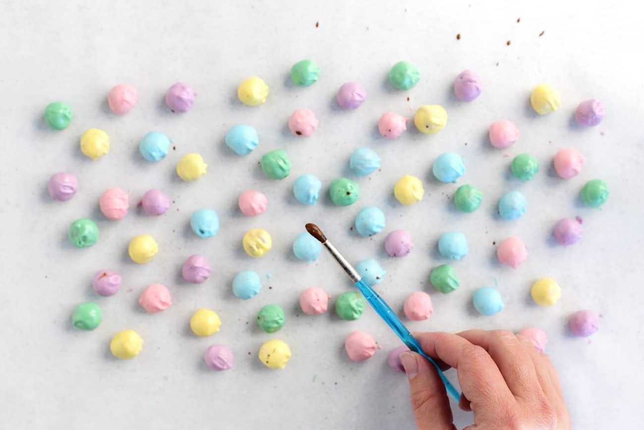 splattering cocoa speckles on the colorful pretzel nuggets with a paintbrush