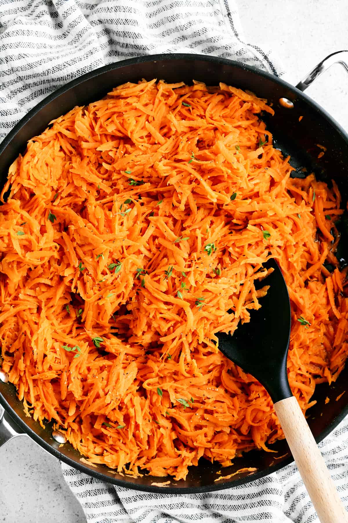 a spatula in the shredded carrots which are in a pan