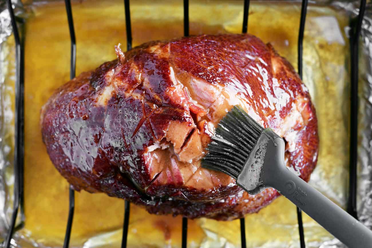 a basting brush and a ham on the roasting rack