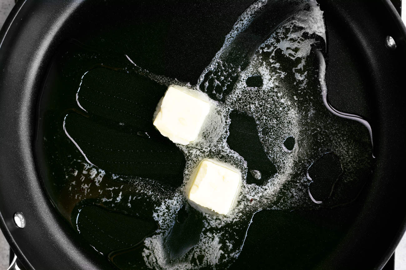 Two pats of butter in a black skillet.