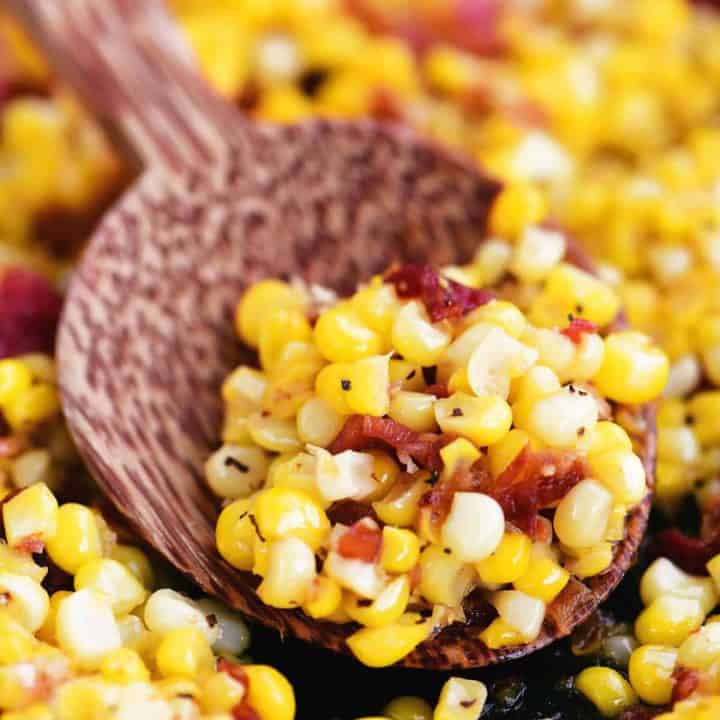a wooden spoon with peppered corn and bacon in it