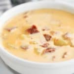 cheesy ham and potato soup in a white bowl
