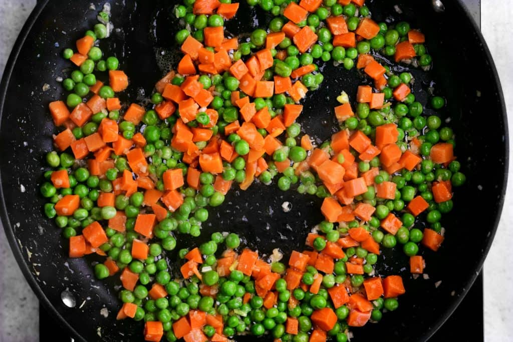 sautéing peas and diced carrots in a skillet
