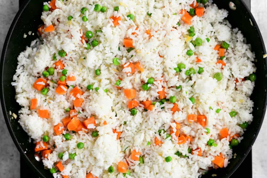 white rice, diced carrots, and peas in a pan