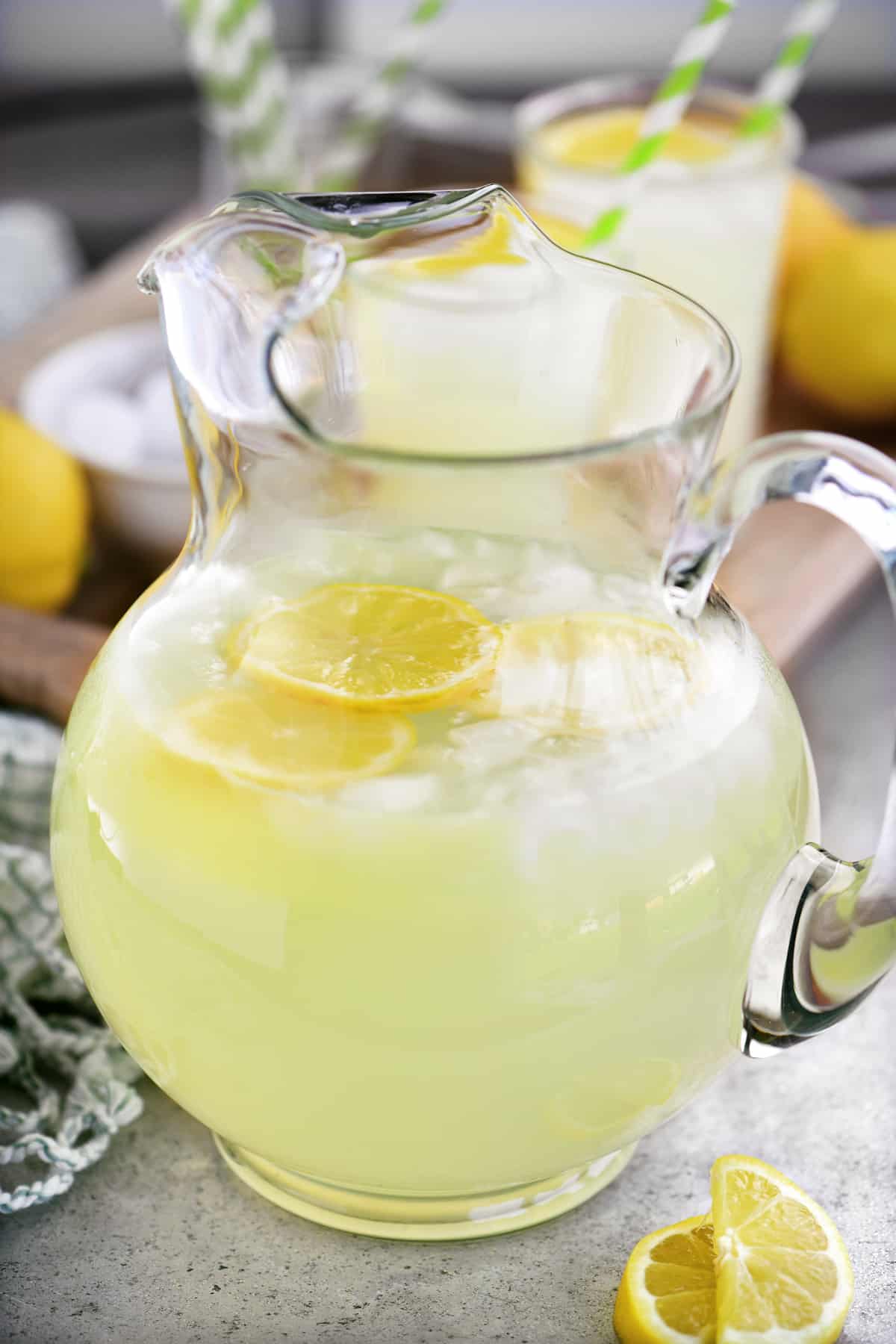 a glass pitcher with lemonade, lemon slices, and ice cubes
