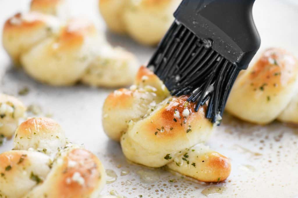 brushing butter and garlic on a baked garlic knot