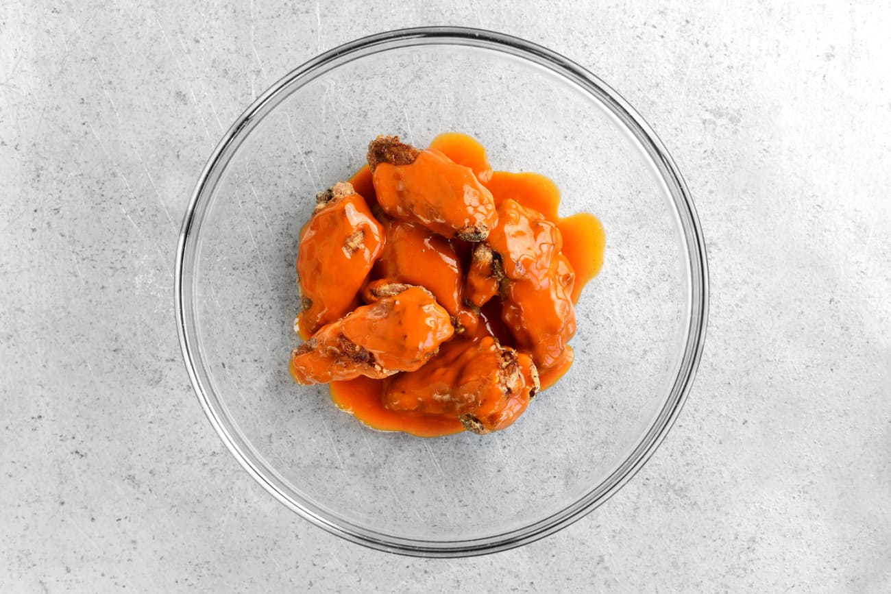 buffalo sauce an chicken wings in a glass bowl