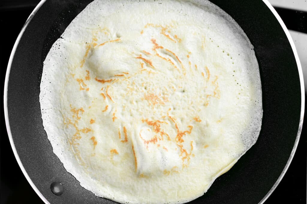 a crepe frying in a black frying pan